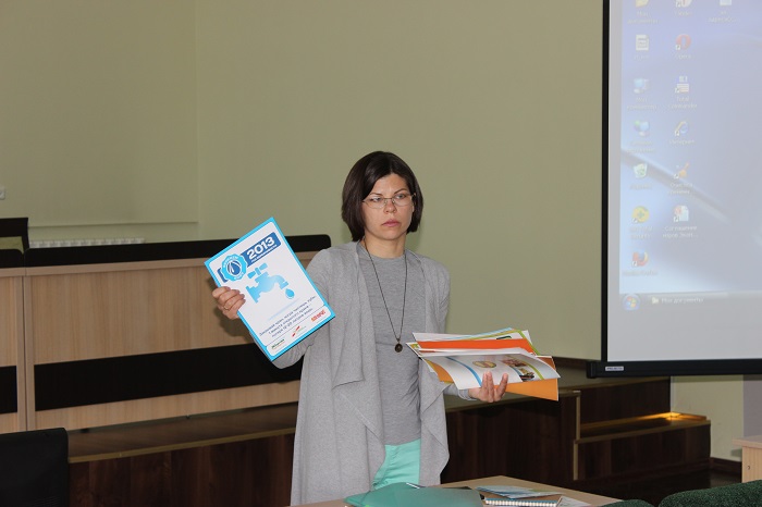 Наталья Андреенко показывает плакаты по энергосбережению